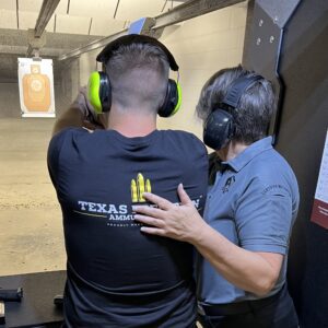 A person being instructed by a trainer inside an indoor shooting range