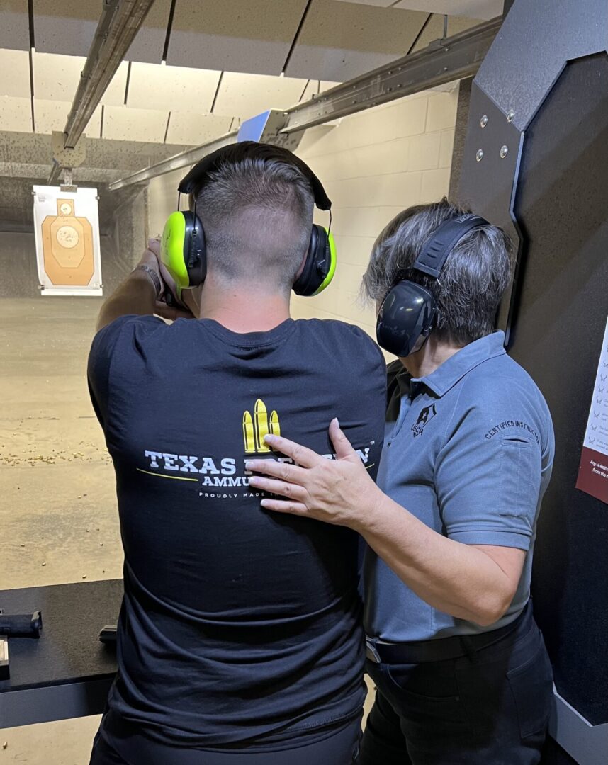 A person being instructed by a trainer inside an indoor shooting range